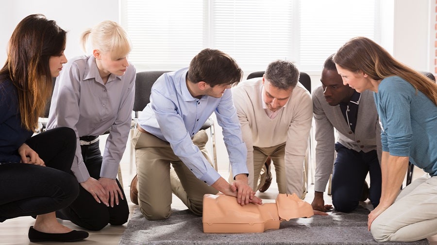 An instructor demonstrates CPR on a dummy