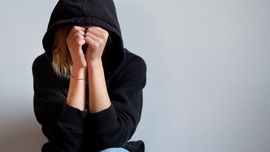 A person wearing a dark hoodie hides their face