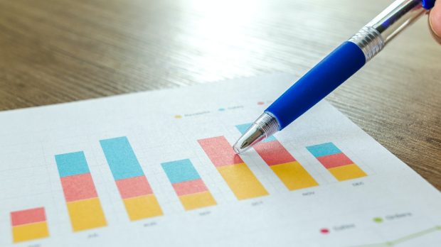 a person holding a pen and pointing at bar graphs