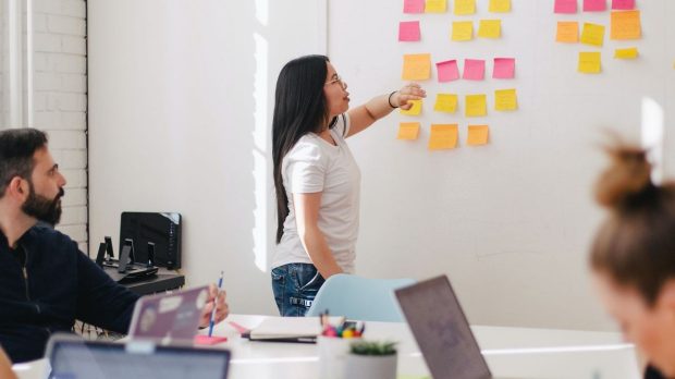 a woman uses sticky notes on a whiteboard